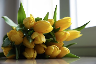 Bunch of beautiful yellow tulip flowers on windowsill, closeup