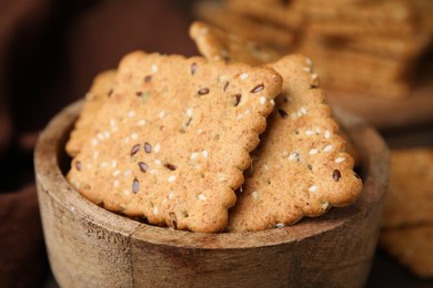 Photo of Cereal crackers with flax and sesame seeds in bowl on blurred background, closeup