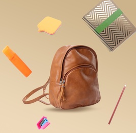 Backpack surrounded by flying school stationery on color background