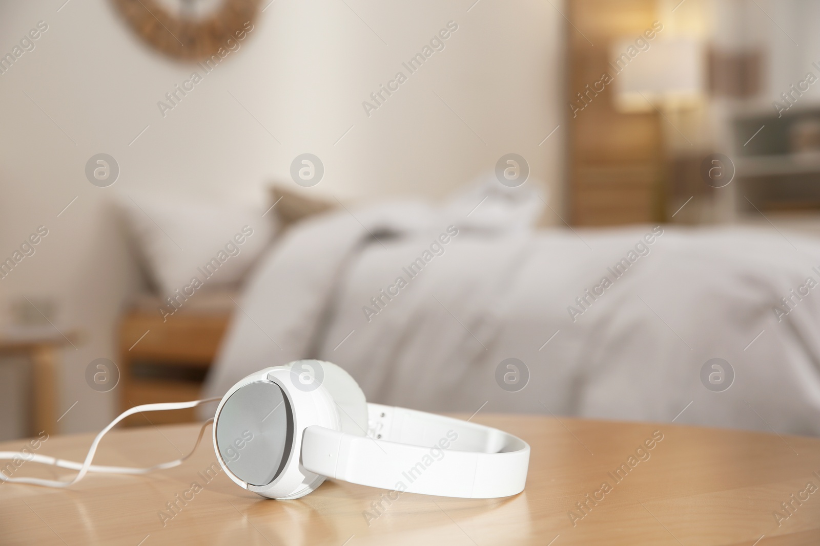 Photo of Stylish modern headphones with earmuffs on table against blurred background, space for text