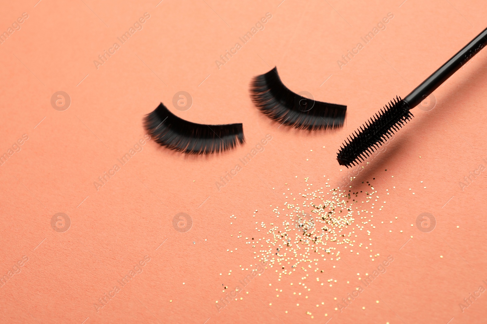 Photo of False eyelashes and mascara on orange background, space for text