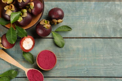 Photo of Purple mangosteen powder and fruits on light blue wooden table, flat lay. Space for text