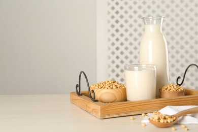 Photo of Soy milk and beans on wooden table, space for text