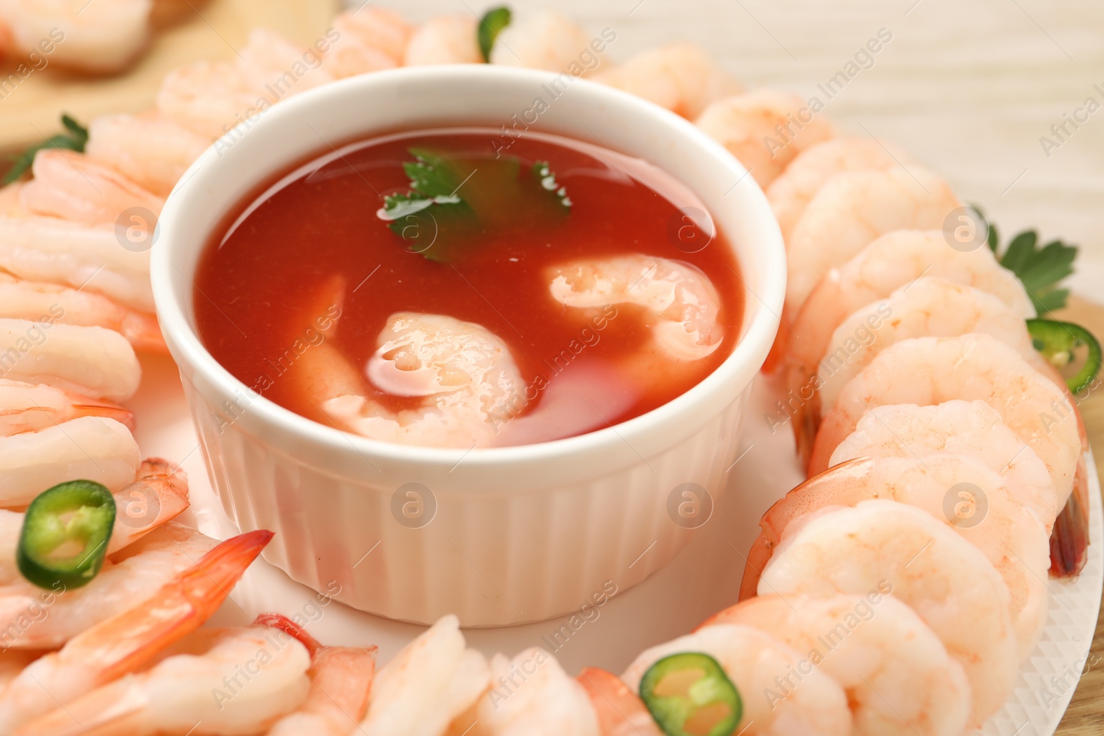 Photo of Tasty boiled shrimps with cocktail sauce, chili and parsley on table, closeup