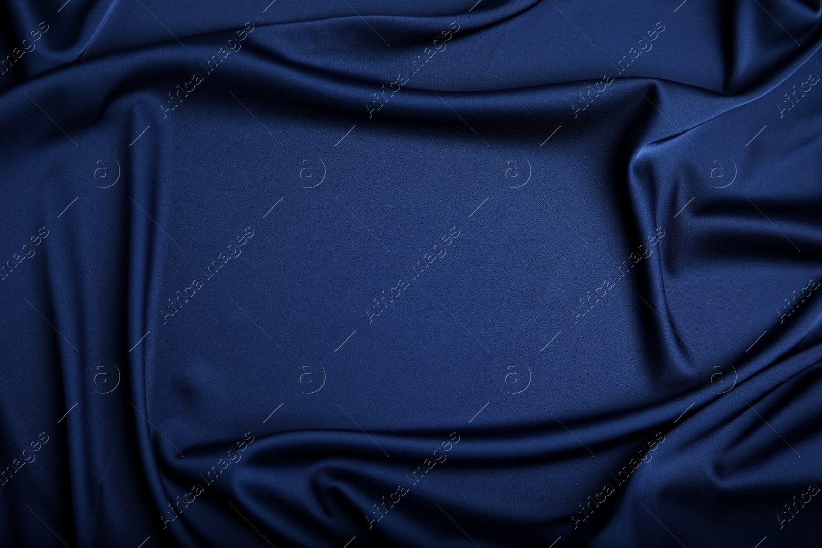 Photo of Crumpled dark blue silk fabric as background, top view. Space for text