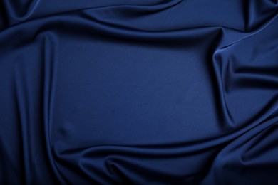 Photo of Crumpled dark blue silk fabric as background, top view. Space for text