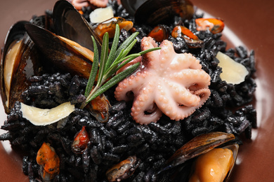 Photo of Delicious black risotto with seafood in plate, closeup