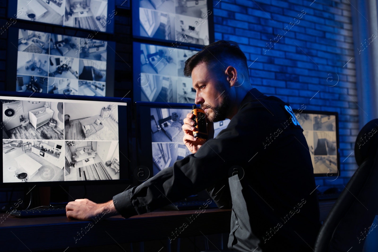 Photo of Male security guard with portable transmitter monitoring modern CCTV cameras indoors