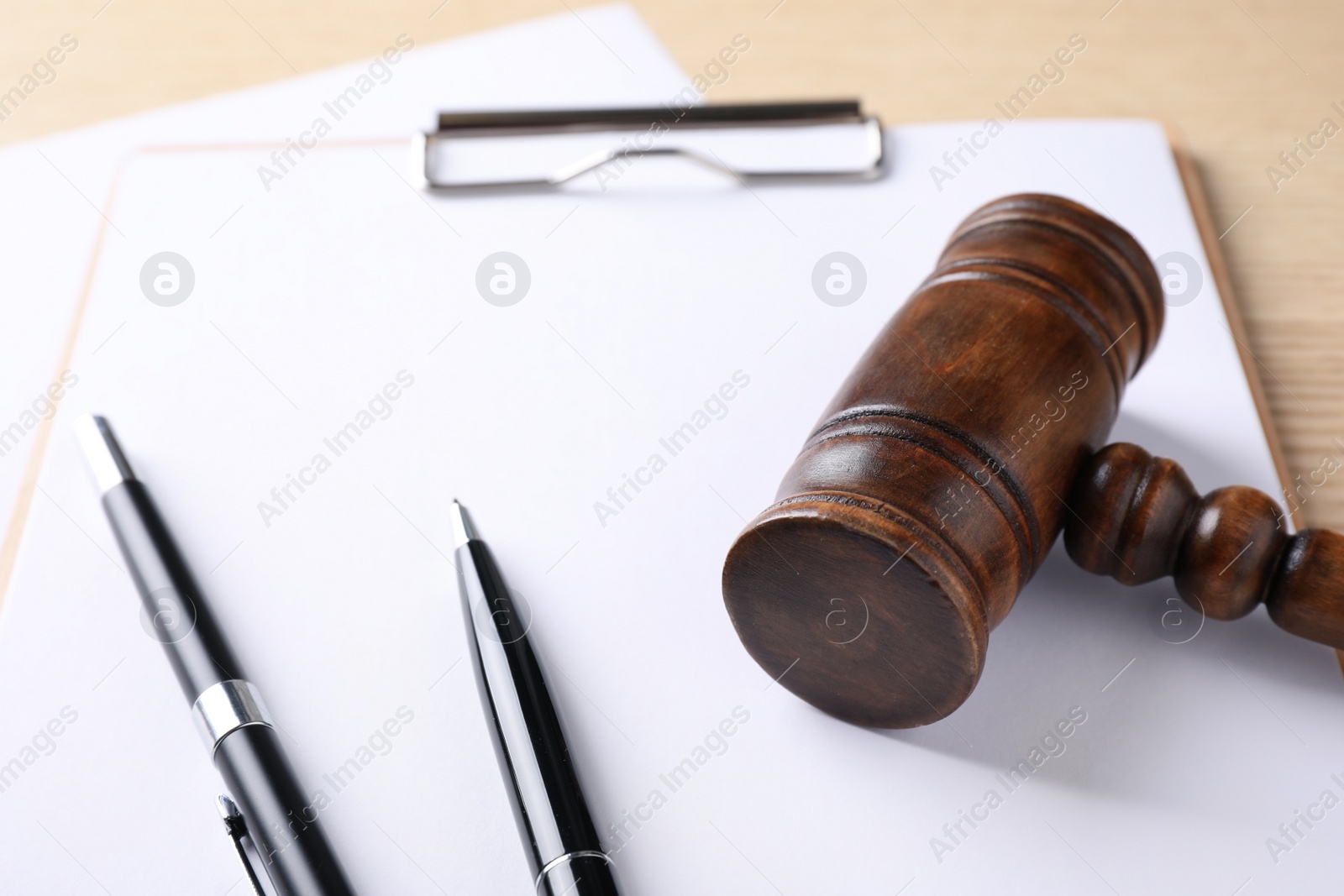Photo of Clipboard with gavel on wooden table. Domestic violence law concept