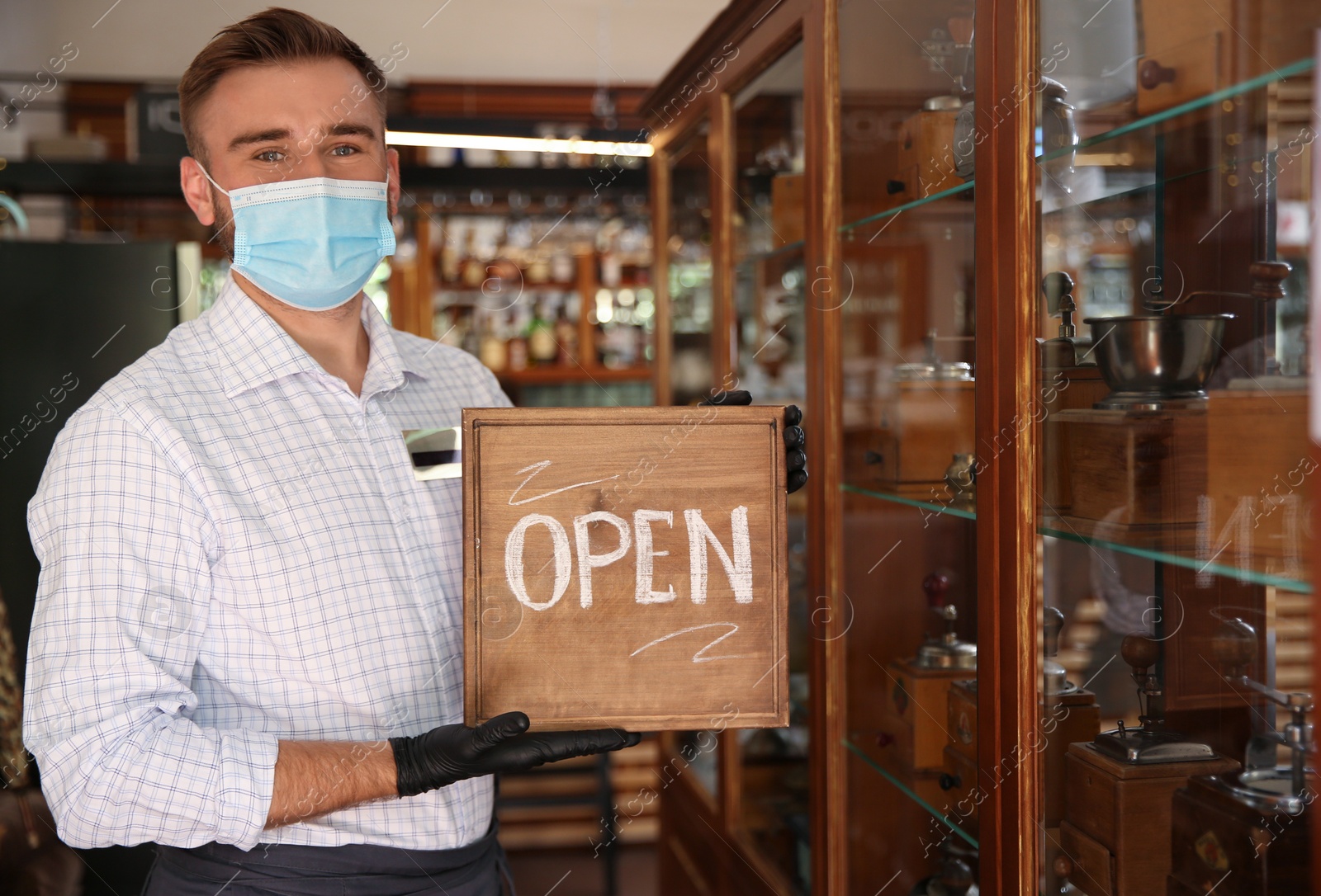 Photo of Waiter holding OPEN sign in restaurant. Catering during coronavirus quarantine