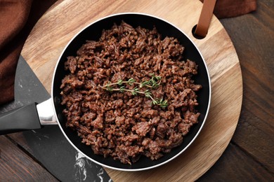 Photo of Fried ground meat and thyme in frying pan on wooden table, top view