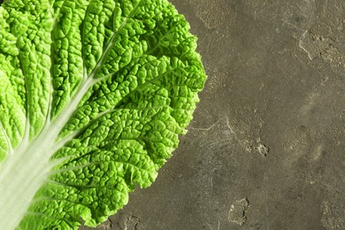 Photo of Fresh Chinese cabbage leaf on gray textured table, top view. Space for text