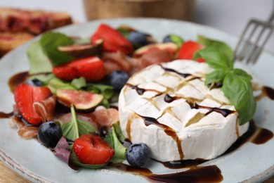 Delicious salad with brie cheese, berries and balsamic vinegar on plate, closeup