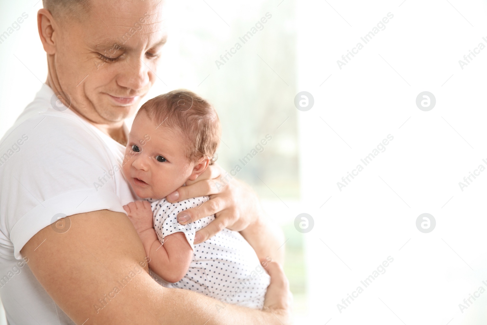 Photo of Man with his newborn baby on light background. Space for text