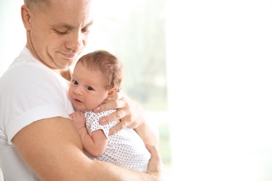 Photo of Man with his newborn baby on light background. Space for text