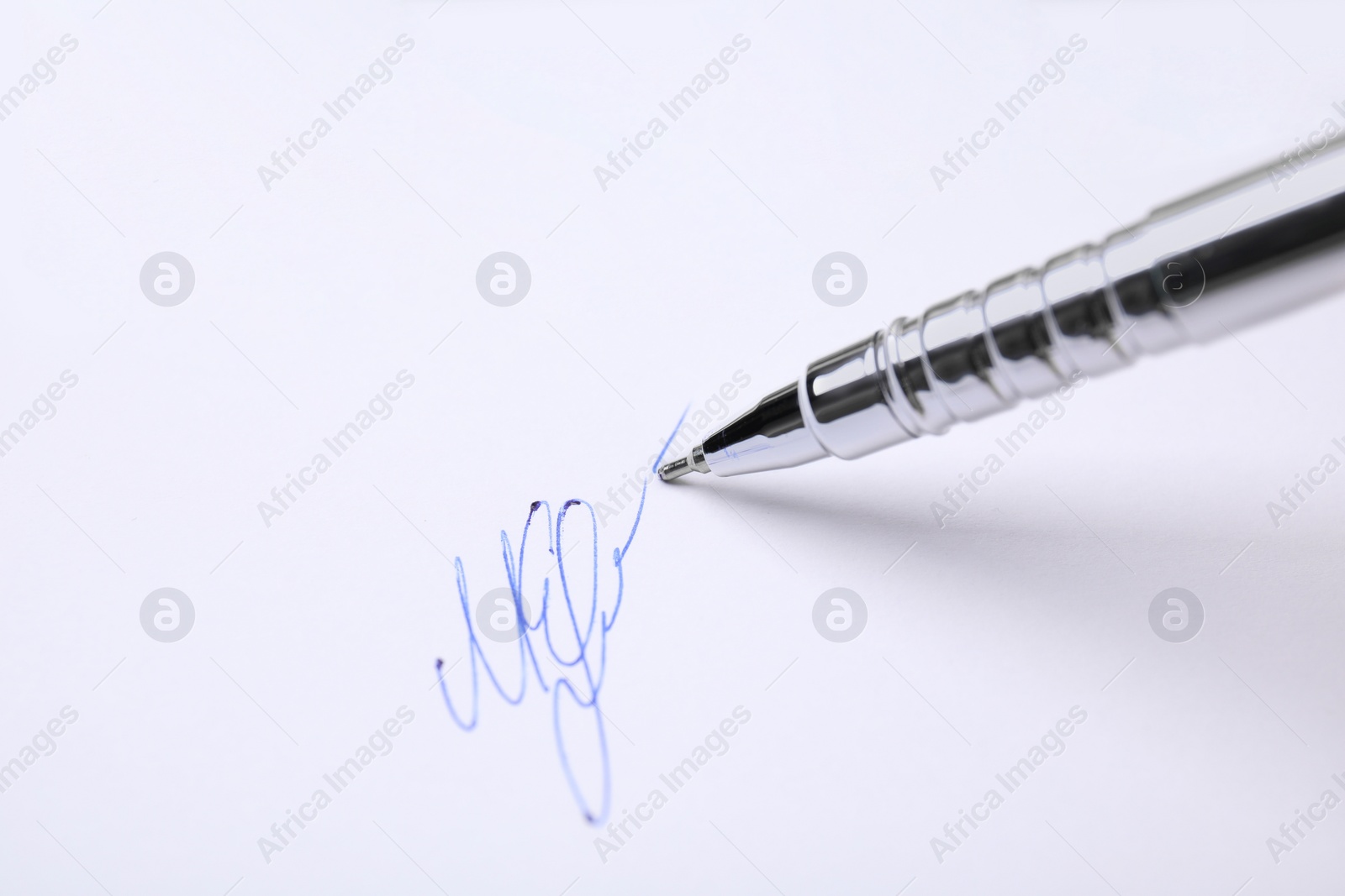 Photo of Signing on sheet of white paper with pen, closeup