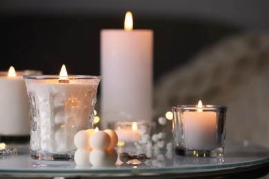 Burning candles and jewelry on table indoors