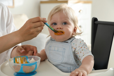 Mother feeding her cute little baby with healthy food at home