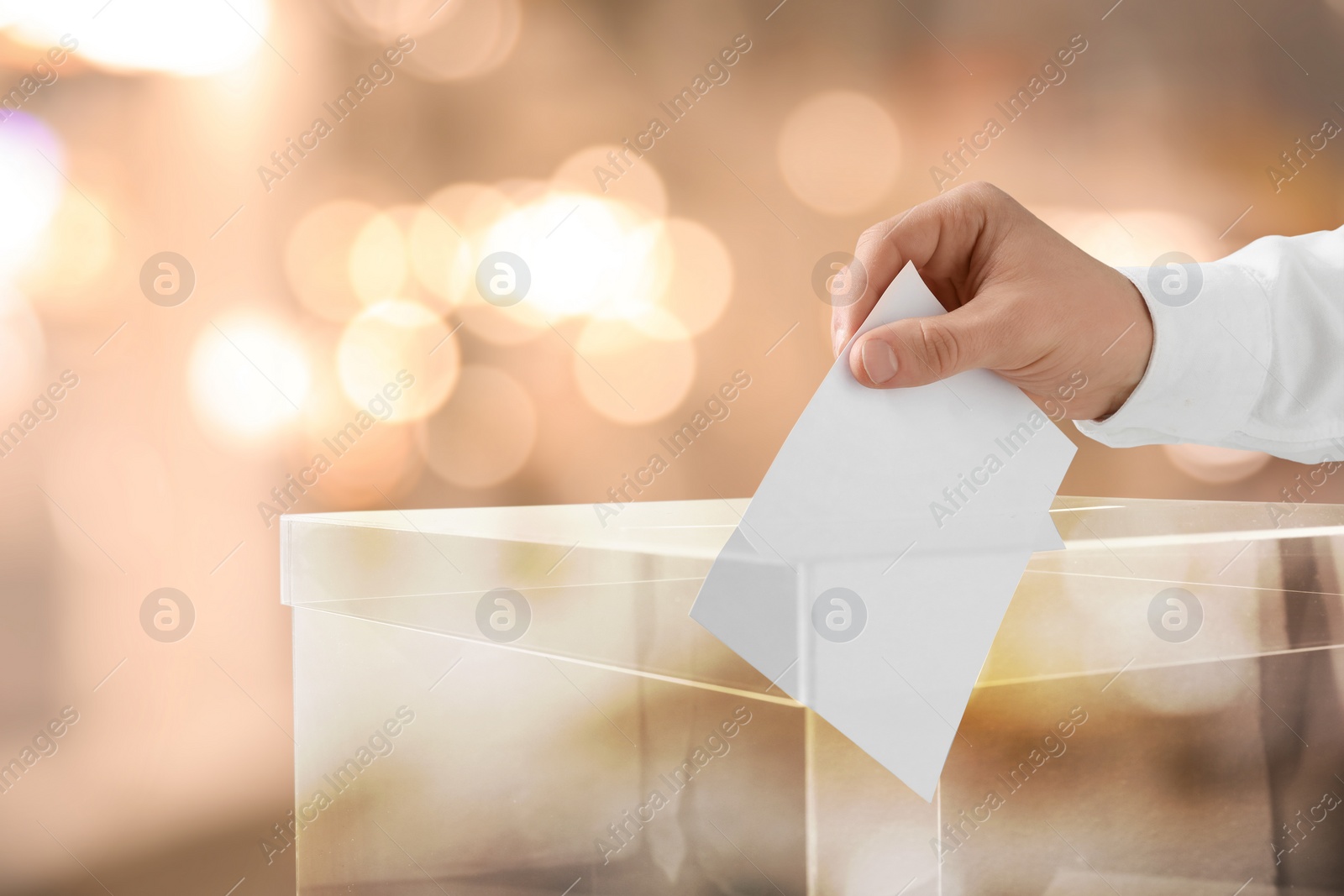 Image of Man putting his vote into ballot box indoors, closeup