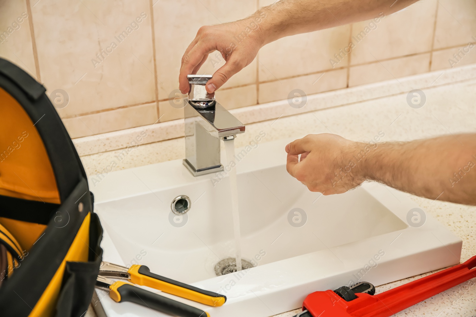 Photo of Professional plumber fixing sink, closeup of hands