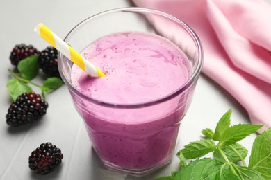 Photo of Delicious blackberry smoothie in glass and berries on white table, closeup