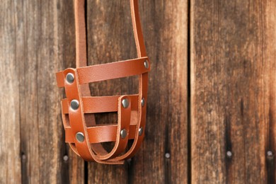 Photo of Brown dog muzzle hanging near wooden fence, closeup. Space for text