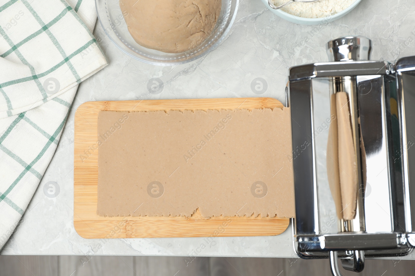 Photo of Preparing dough for soba (buckwheat noodles) with pasta maker at light grey table, flat lay