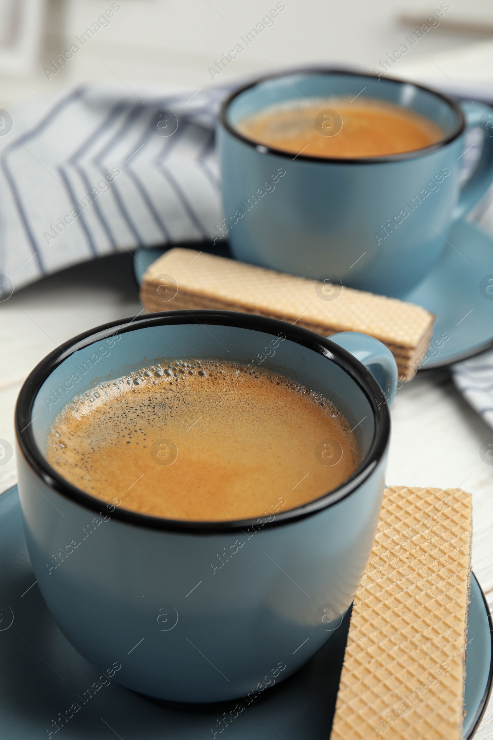 Photo of Delicious wafers and coffee for breakfast on table, closeup