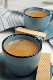 Delicious wafers and coffee for breakfast on table, closeup