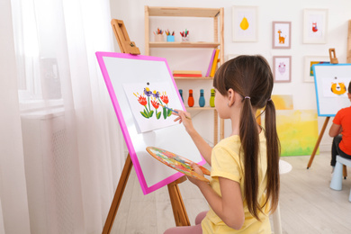 Cute little child painting during lesson in room