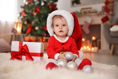 Photo of Cute little baby in Christmas costume sitting on fur rug at home