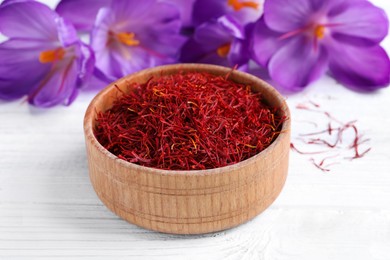 Photo of Dried saffron and crocus flowers on white wooden table, closeup