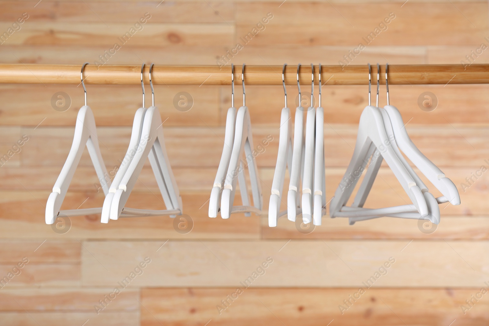 Photo of Rack with clothes hangers on wooden background