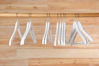 Rack with clothes hangers on wooden background