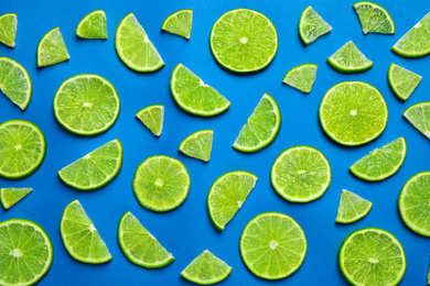 Photo of Juicy fresh lime slices on blue background, flat lay