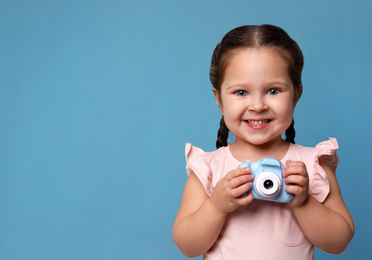 Photo of Little photographer with toy camera on light blue background. Space for text