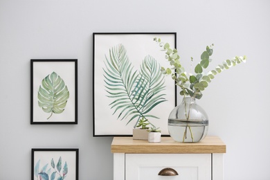 Photo of Vase with fresh eucalyptus branches on cabinet in room. Interior design
