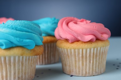 Photo of Delicious cupcakes with bright cream on blue background, closeup