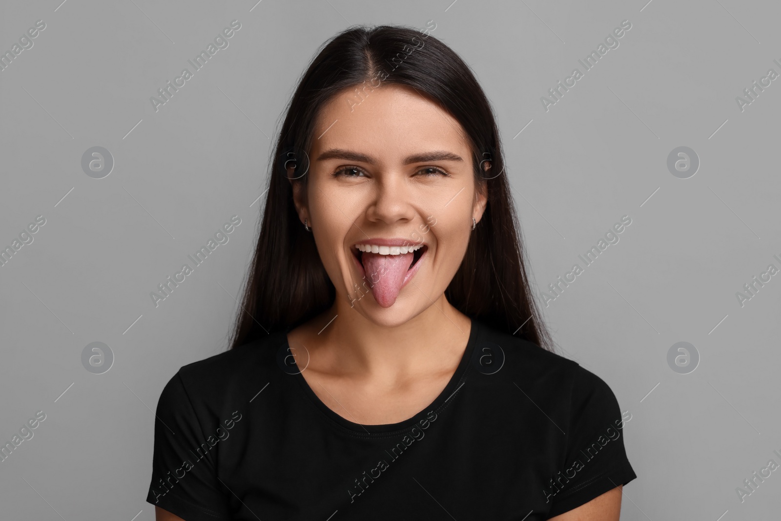 Photo of Personality concept. Emotional woman showing tongue on grey background