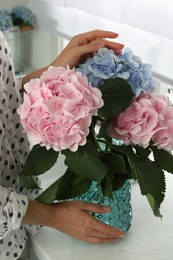 Photo of Woman with beautiful hortensia flowers in kitchen, closeup