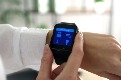 Image of Young man checking electronic wristwatch with Smart Home Interface indoors, closeup