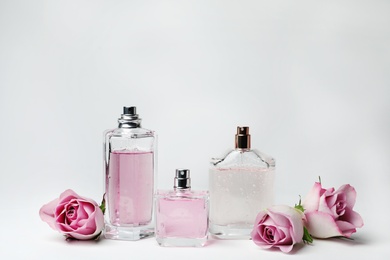 Photo of Composition with transparent bottles of perfume and beautiful flowers on white background