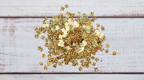 Photo of Pile of many golden sequins on white wooden table, top view
