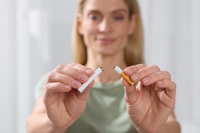 Photo of Woman with broken cigarette on light background, selective focus. Quitting smoking concept