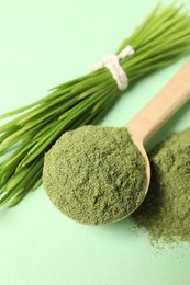 Photo of Wheat grass powder and fresh sprouts on green table, closeup
