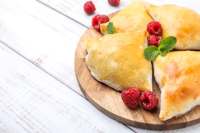 Delicious samosas with raspberries on white wooden table, closeup. Space for text