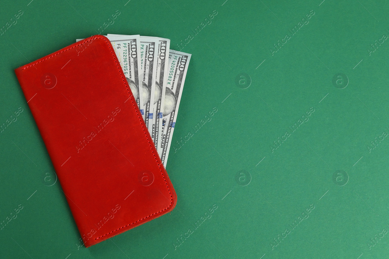 Photo of Money exchange. Wallet with dollar banknotes on green background, top view. Space for text