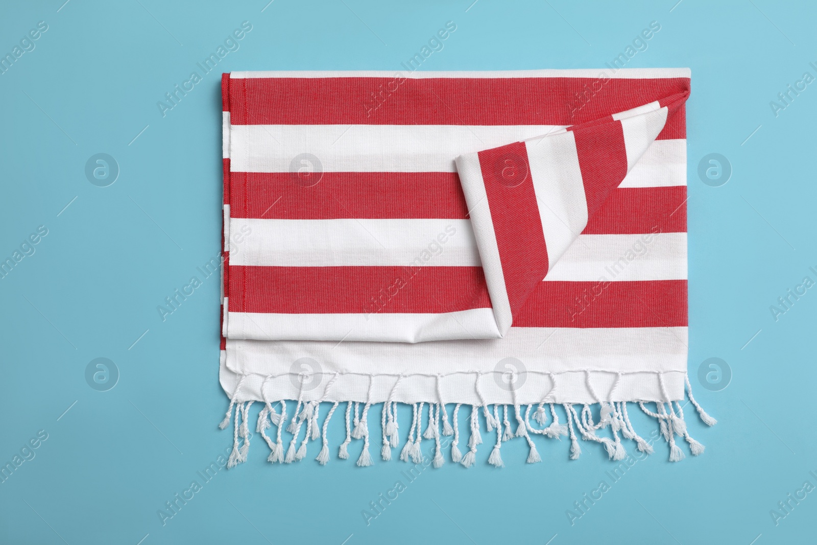 Photo of Folded striped beach towel on light blue background, top view