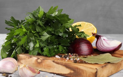 Bunch of fresh parsley, lemon, onion, garlic and spices on grey textured table