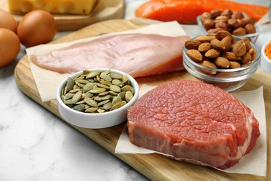 Fresh meat and other products on white table, closeup. Sources of essential amino acids